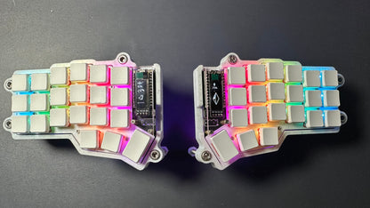 Corne Choc RGB wireless split keyboard — white case, per-key RGB lighting and OLED screens showing Bluetooth and battery, top-down view