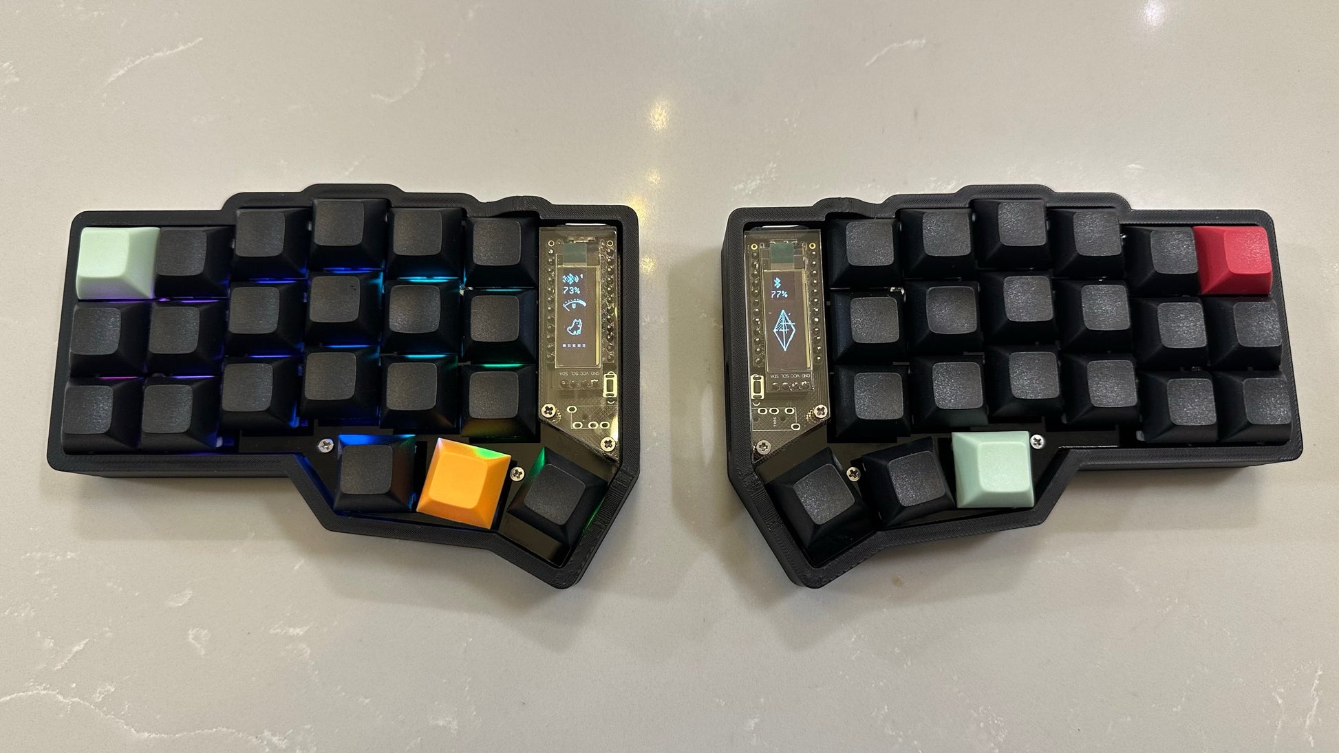 black keycaps with mint, red & orange accent keys, RGB on Corne MX wireless split keyboard — black case with black DSA keycaps and mint, red and orange accent keys, RGB lighting top-down view