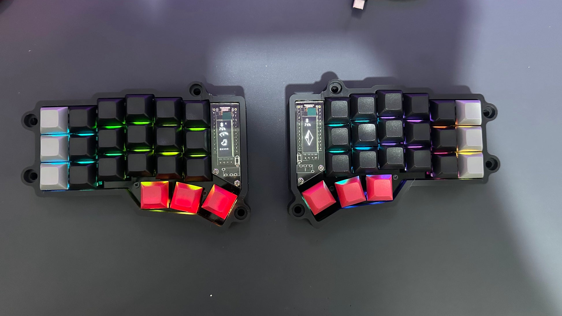 Corne MX wireless split keyboard — black case with black and white keycaps and red thumb keys, per-key RGB lighting, top-down view