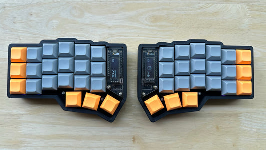 Corne MX wireless split keyboard — black case with gray and orange accent DSA keycaps, top-down view