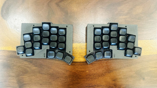 KLP Lamé sculpted low profile keycap set in black, fitted to a Totem split keyboard — both halves, top-down view showing the column stagger and thumb cluster